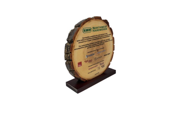 Custom wood deal tombstone, featuring transaction text printed on a log section, celebrating the successful reorganization of Northwest Hardwoods.